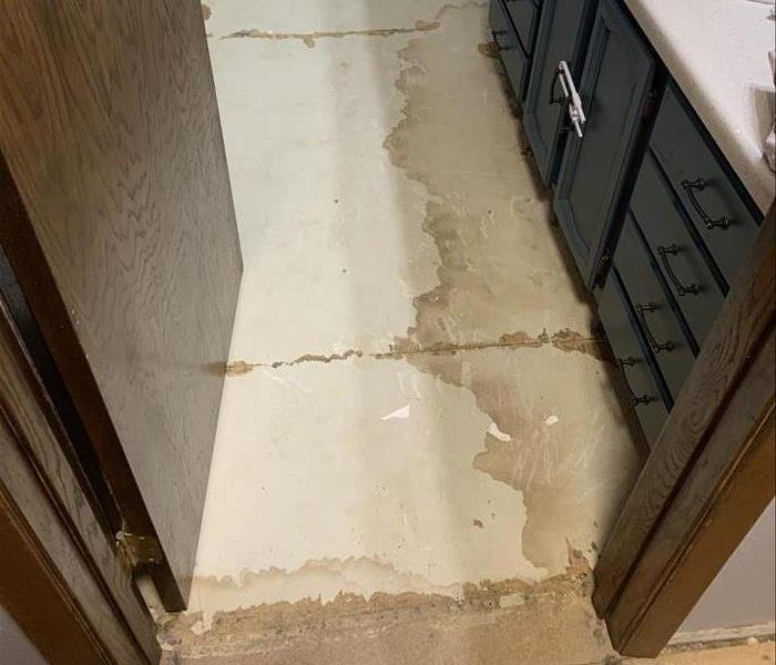 Water damage visible beneath flooring