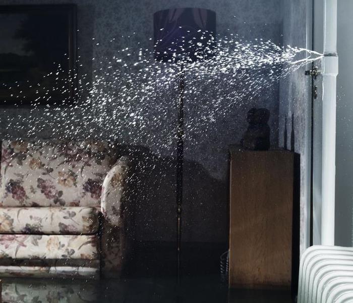 Burst pipe spraying water in to living room of home