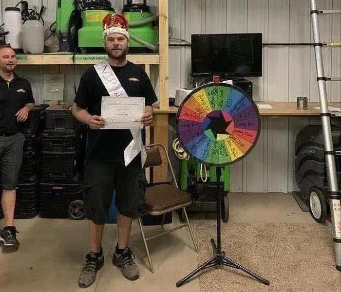 Male SERVPRO Employee Holding Certificate and wearing crown